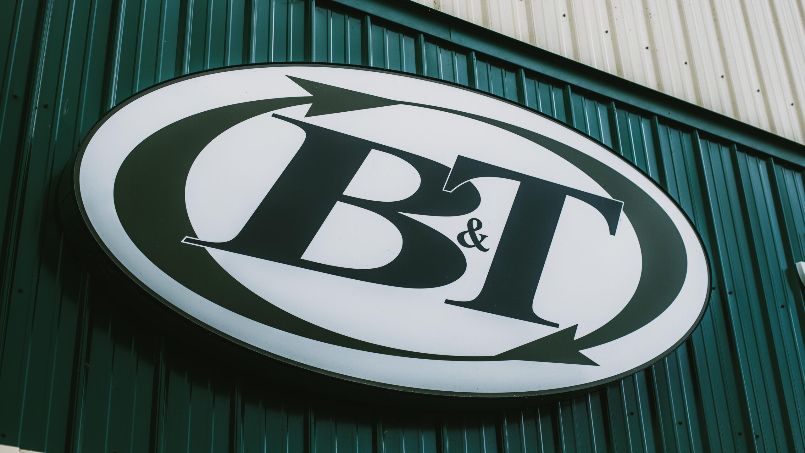 B&T logo sign hanging on green wall